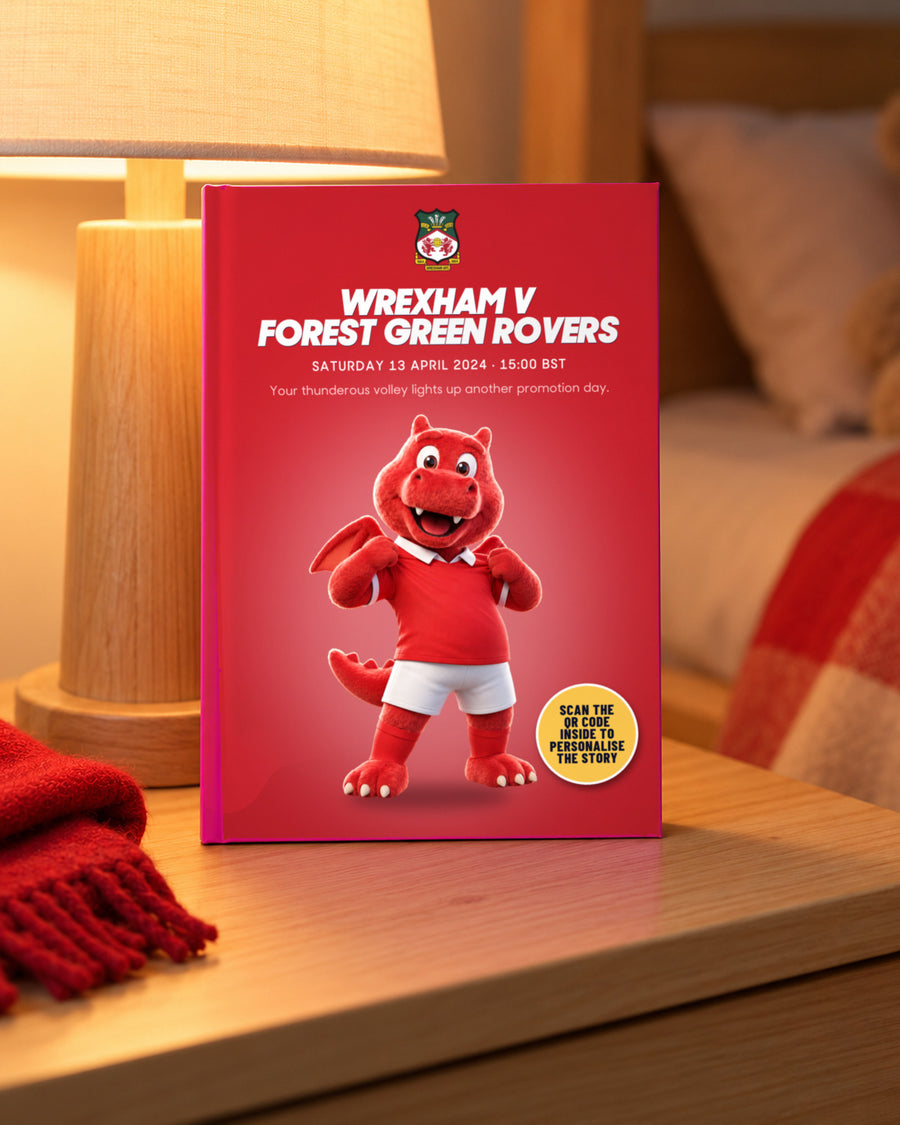 Illustrative image, not a real customer: the book Wrexham v Forest Green Rovers on a bedside table in lamp light, Quick buy edition with Wrex the Dragon.