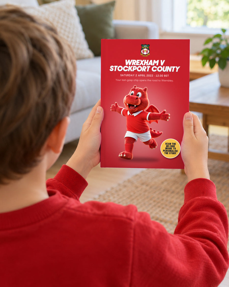 Illustrative image, not a real customer: an illustrated child holding up the book Wrexham v Stockport County, Quick buy edition with Wrex the Dragon.